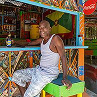 Local black man drinking Carib beer at Charlie's Bar on Happy Hill, Saint George on the west coast of the island of Grenada, Caribbean